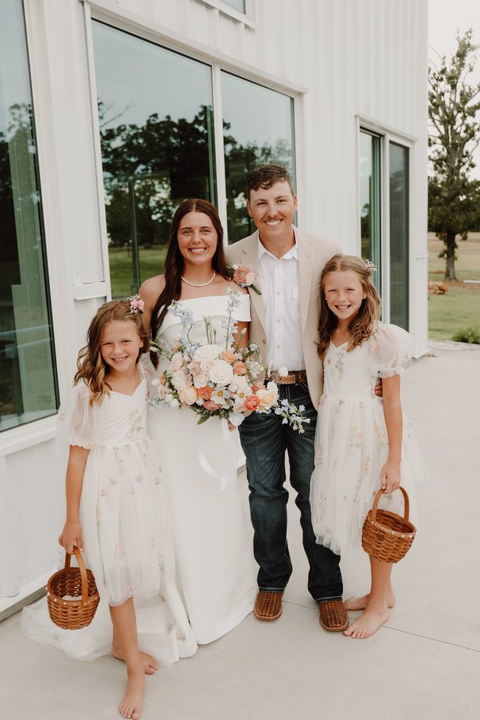 Bride and groom with nieces on the East side of Bella Rosa Venue near Tulsa with huge windows in the background