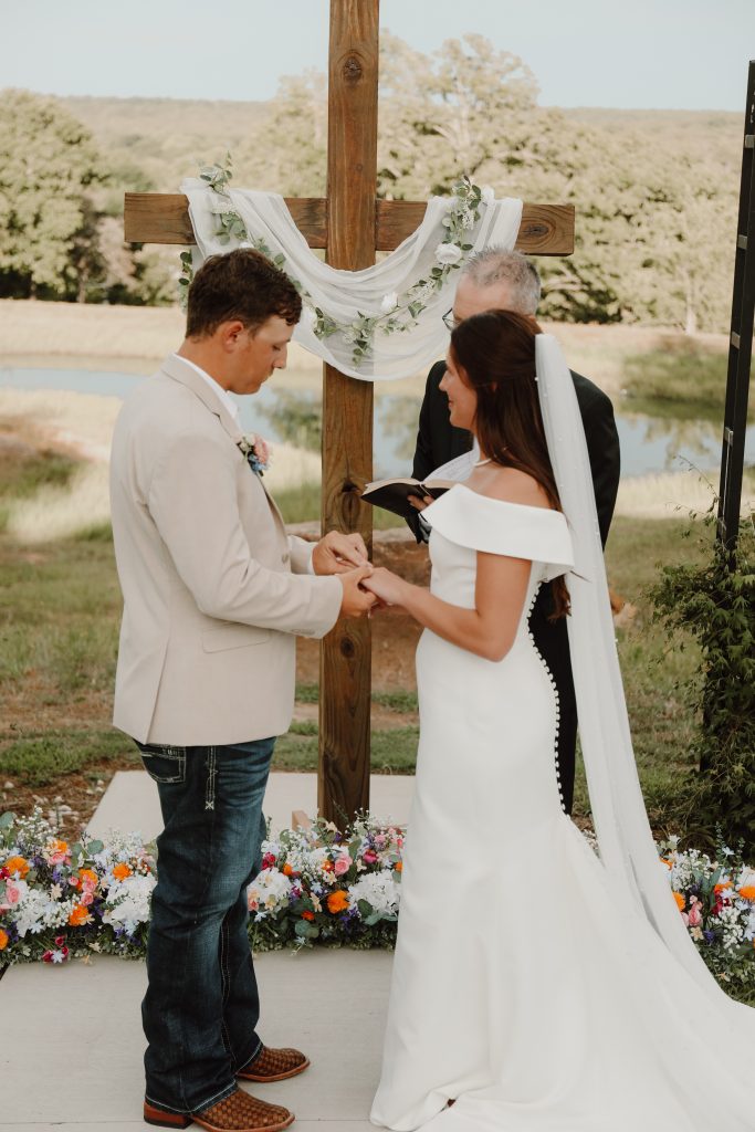Vows at the cross in Bella Rosa Venue's outdoor ceremony site with skyline views near Tulsa, OK